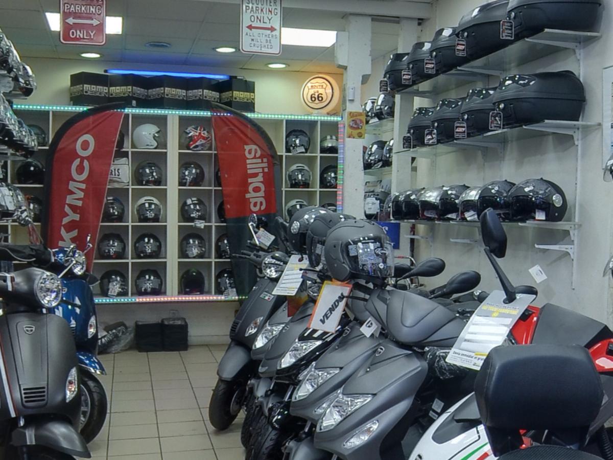 Le mur de casques et les top cases du magasin, derrière une rangée de scooters