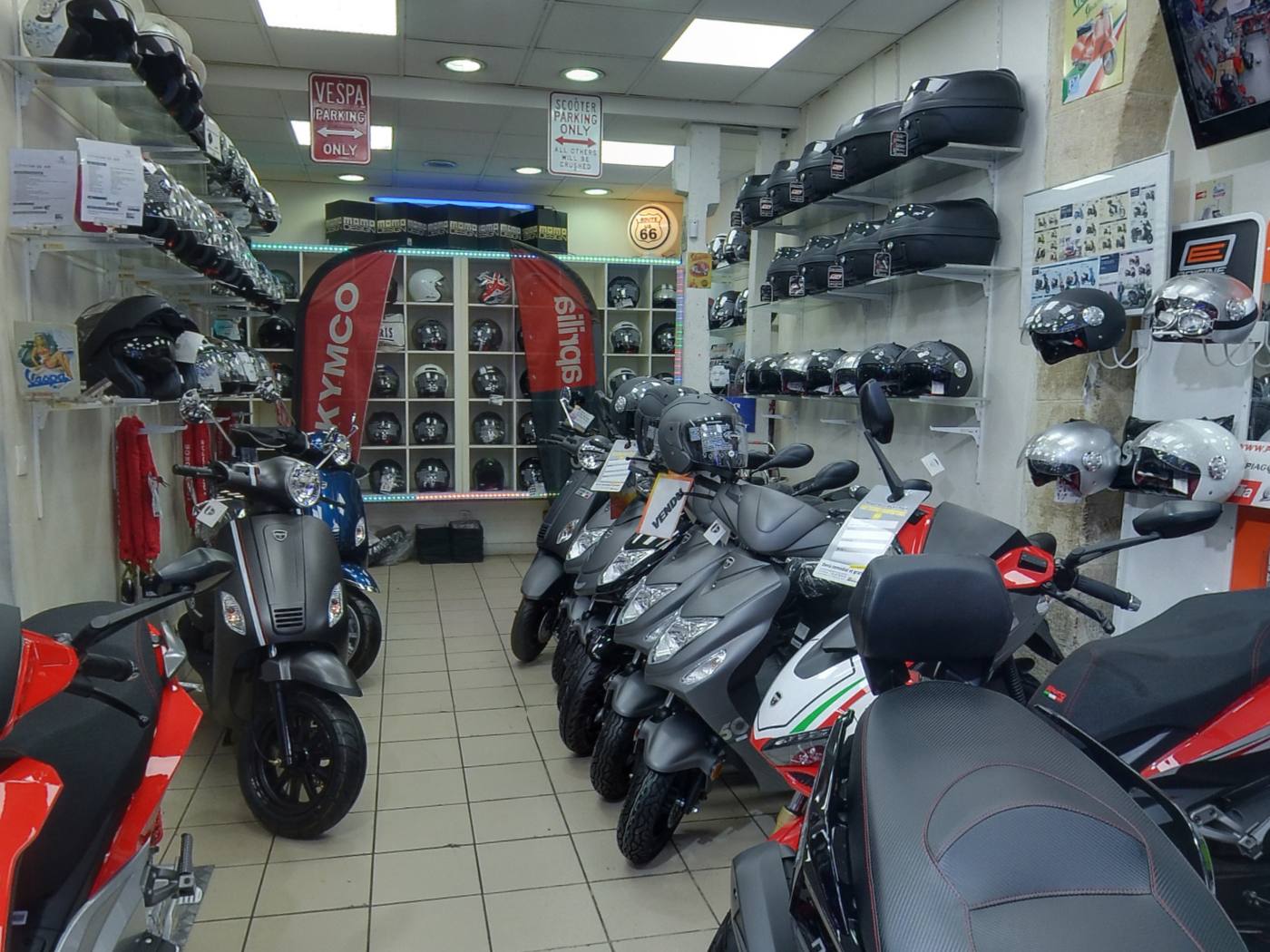 L'intérieur du magasin Paris Scooter: scooters alignés, mur de casques et top cases